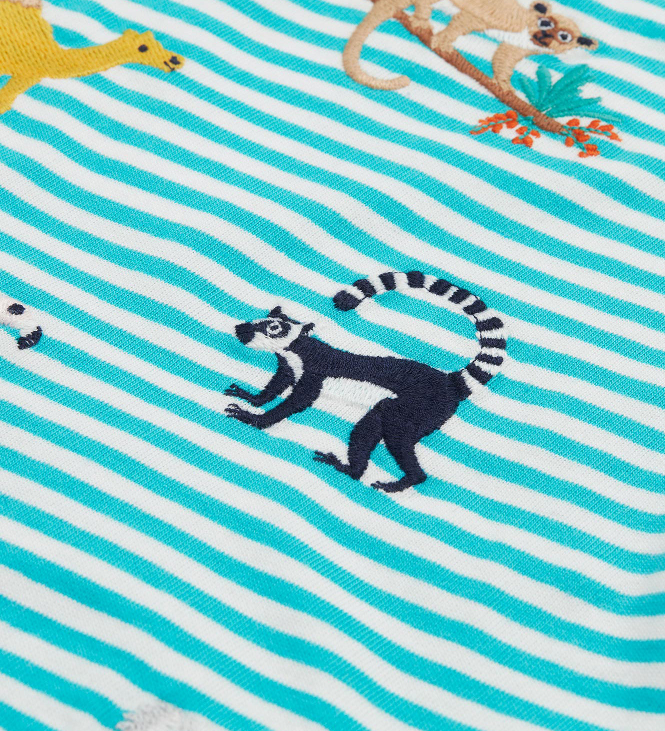 A close up of the Frugi kids moss stripe wildlife t-shirt. Showing the lemur applique detail next to the camel applique on blue and white stripe organic cotton fabric.