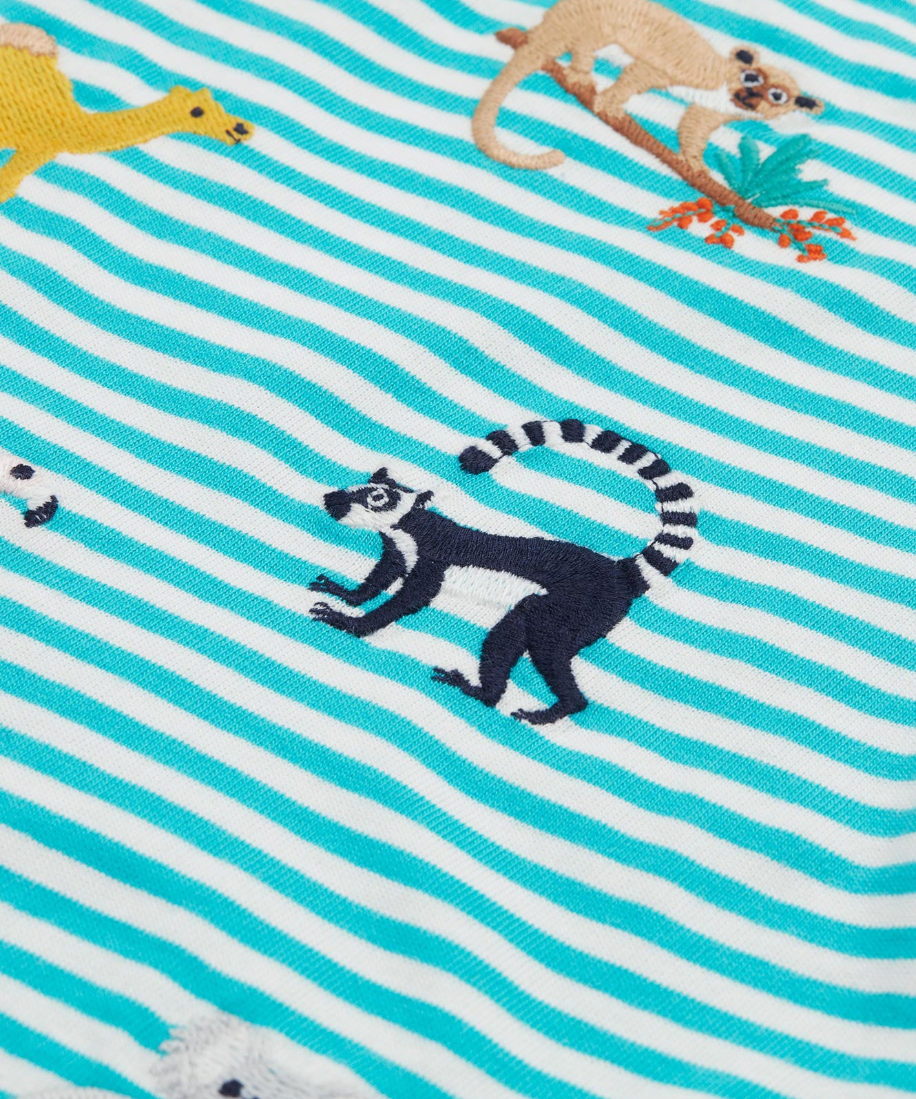 A close up of the Frugi kids moss stripe wildlife t-shirt. Showing the lemur applique detail next to the camel applique on blue and white stripe organic cotton fabric.