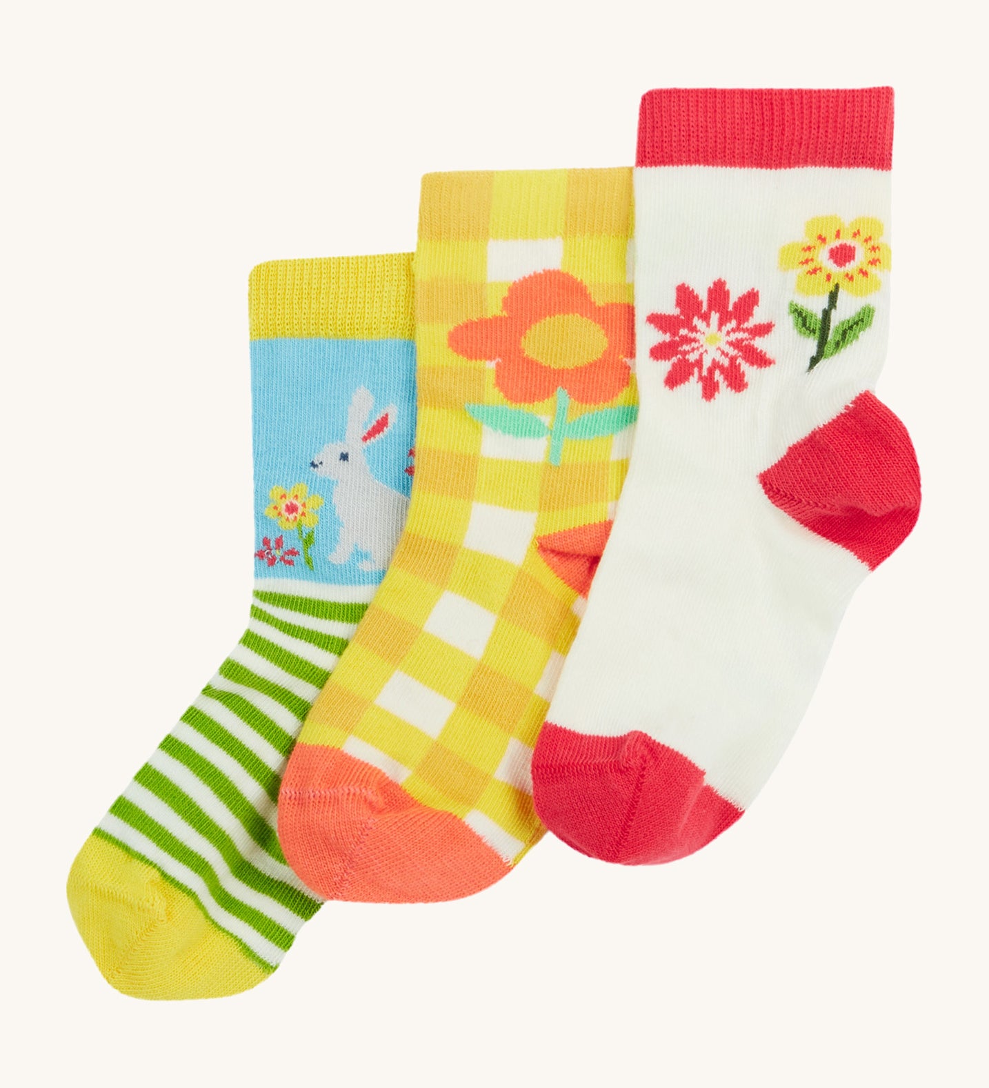 Frugi kids spring 3 pack socks - GOTS organic kids socks which features a white sock with a pink trim and flowers. A yellow gingham sock with a flower design and a green striped sock with a rabbit design.