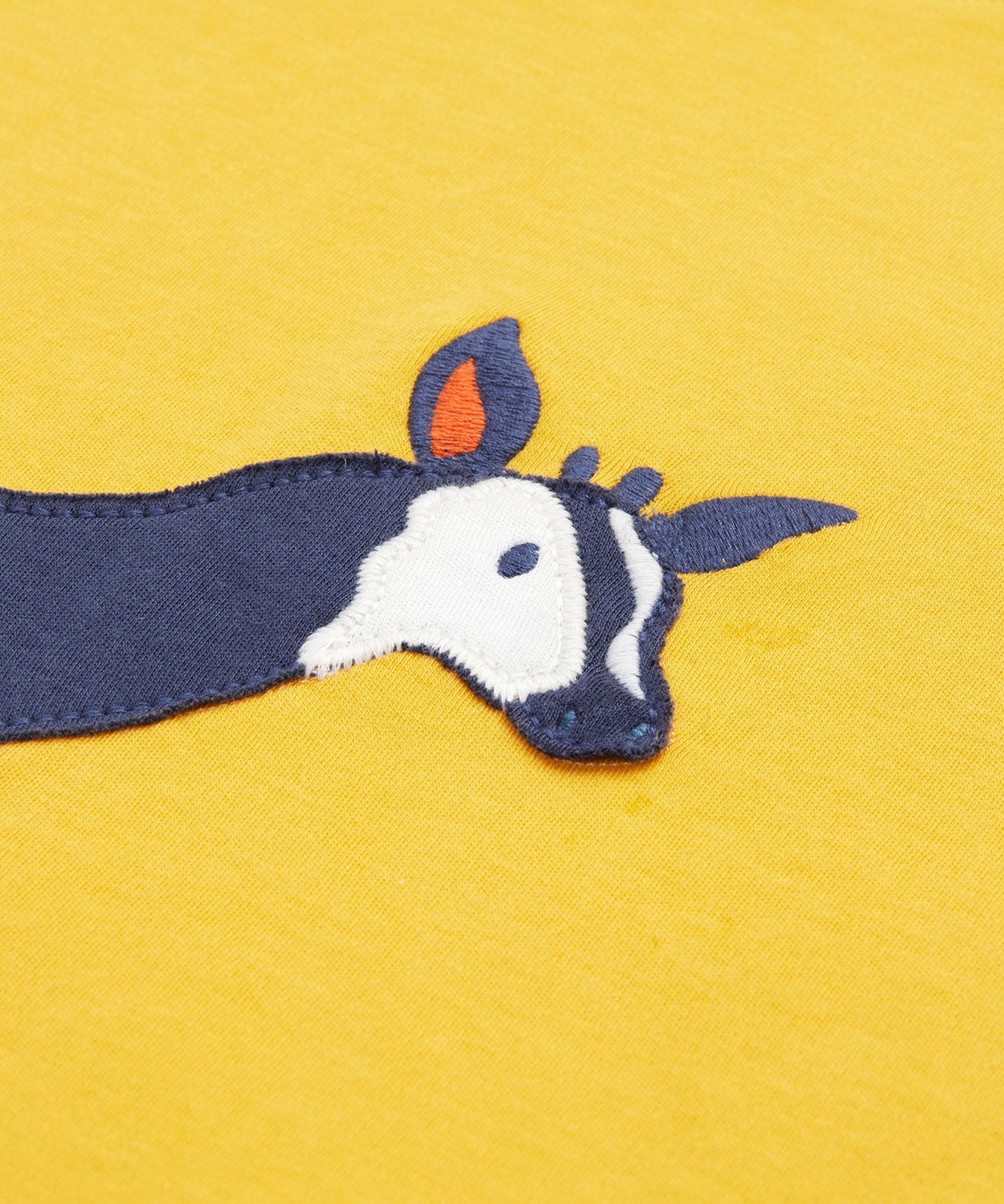 Close up of the Frugi kids bumblebee okapi short sleeve t-shirt. showing the head of the okapi animal appliqué on yellow organic cotton fabric