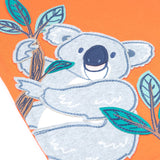 Close up of the Frugi kids orange koala t-shirt. Showing the grey koala applique hanging on embroidered bamboo shoots on light orange organic fabric