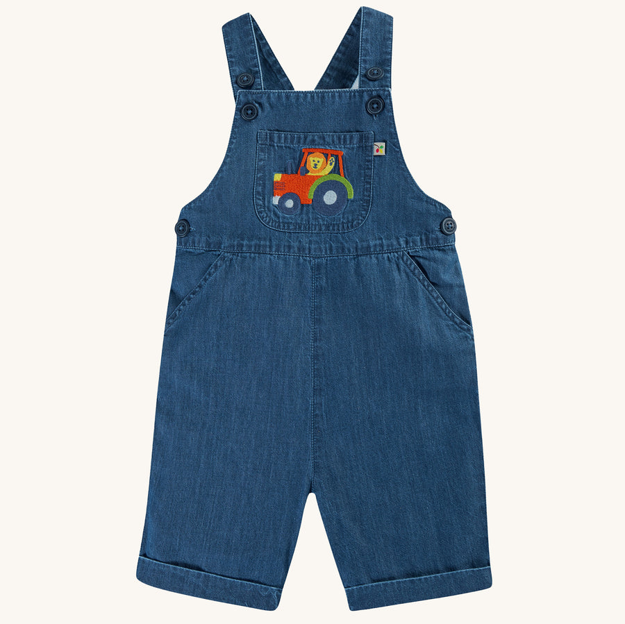 Frugi Organic Carnkie Chambray Denim Dungarees - Tractor. Chambray design dungarees with a tractor embroidered patch on the pocket. Made from soft organic cotton, with adjustable popper fastenings on the straps and an elasticated waist. On a cream backgro