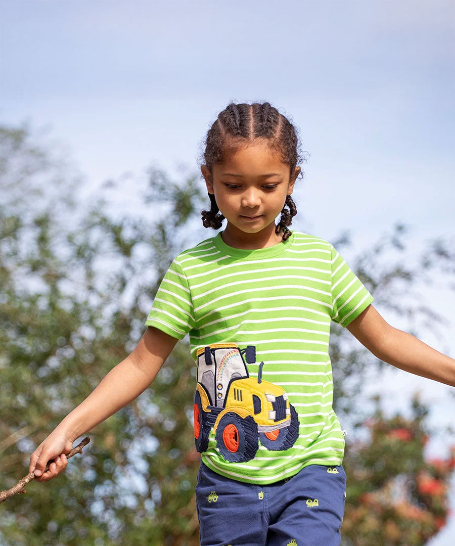 Achild wearing the Frugi kids sid t-shirt - GOTS organic cotton kids short sleeve t-shirt in green and white stripe with a yellow tractor appliqué to the left side