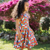 A child wearing the Frugi Over The Rainbow print Spring Skater Dress