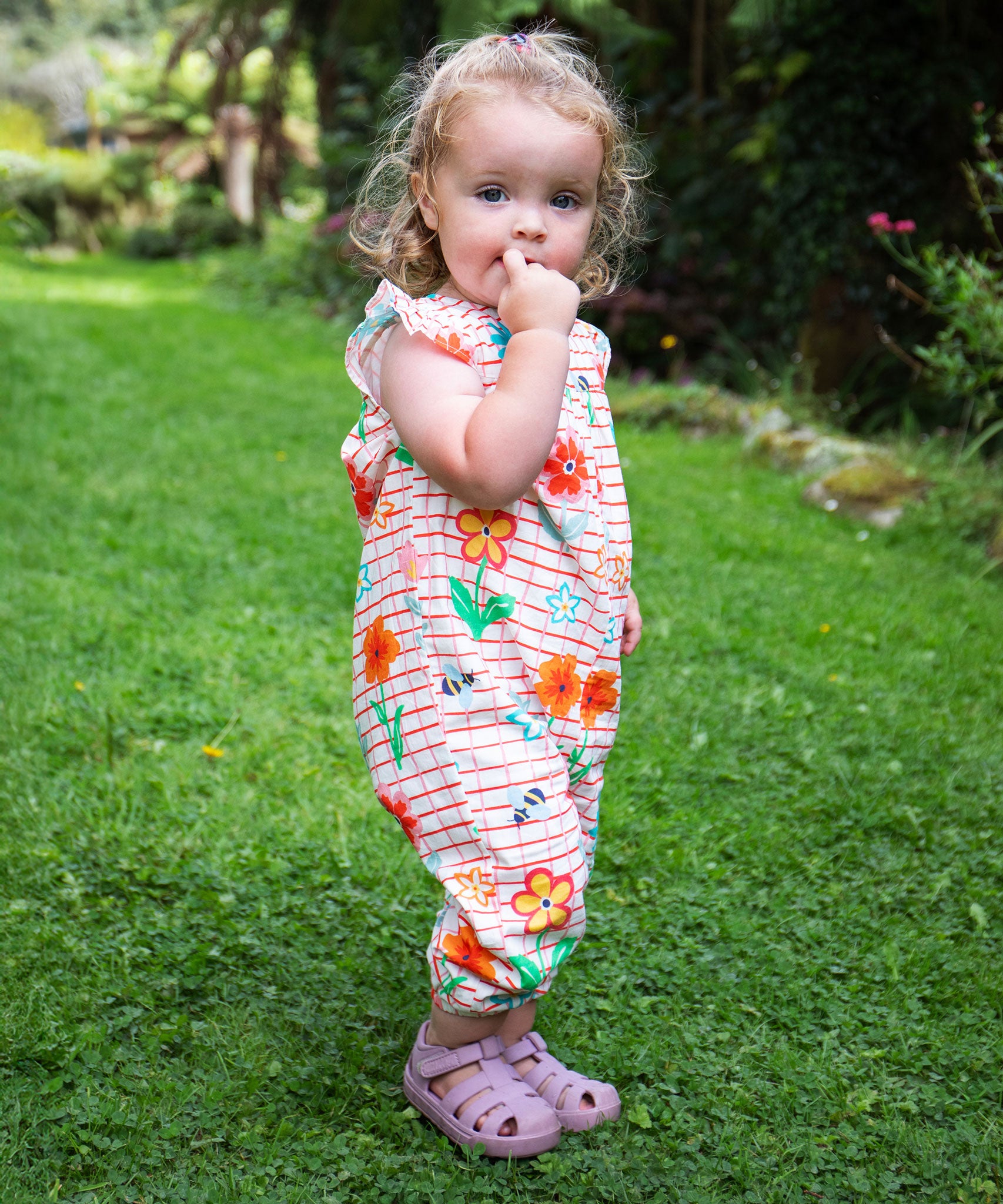 A child wearing the Frugi Paint A Floral Lula organic cotton Playsuit