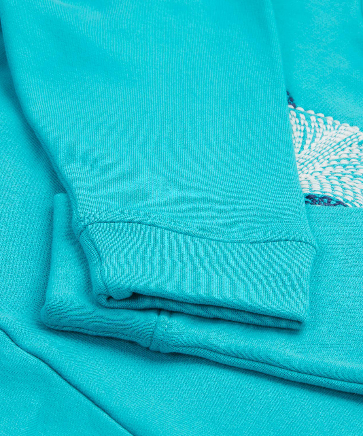 A close up of the Frugi kids oversized blue panda hoodie. Showing the arm cuffs on a light blue organic cotton fabric