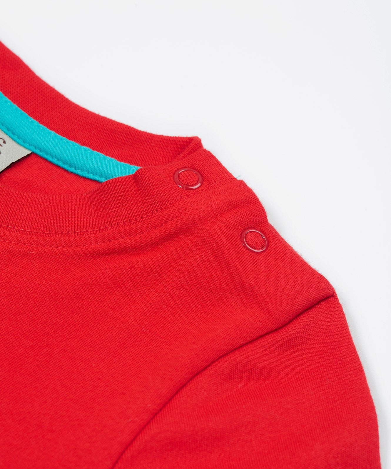 Close up of the Frugi kids strawberry quokka tshirt. Showing the popper fasteners on the shoulder for easy fitting with a light blue trim on inside neck on red organic cotton fabric