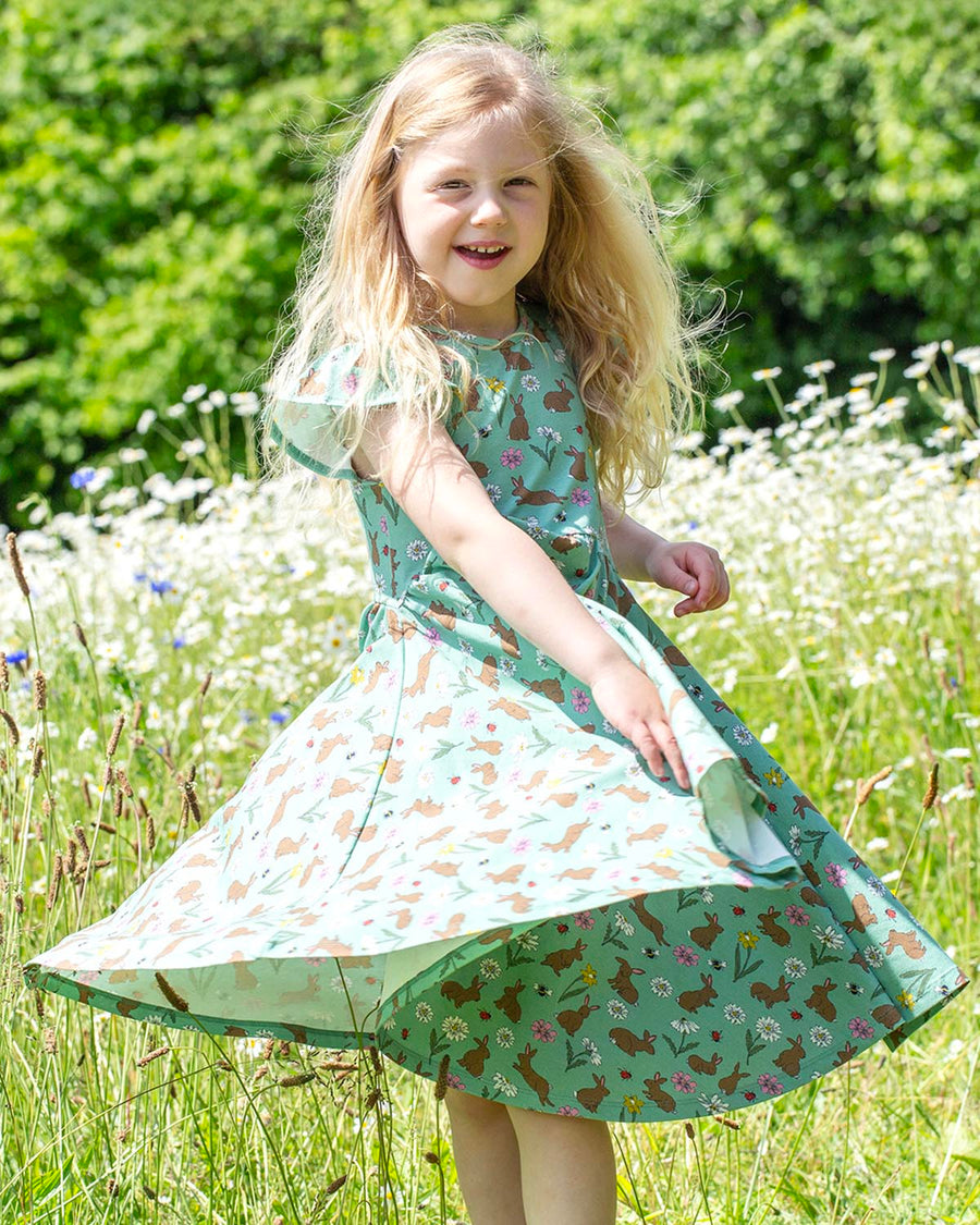 A child happily playing in the sun and picking flowers