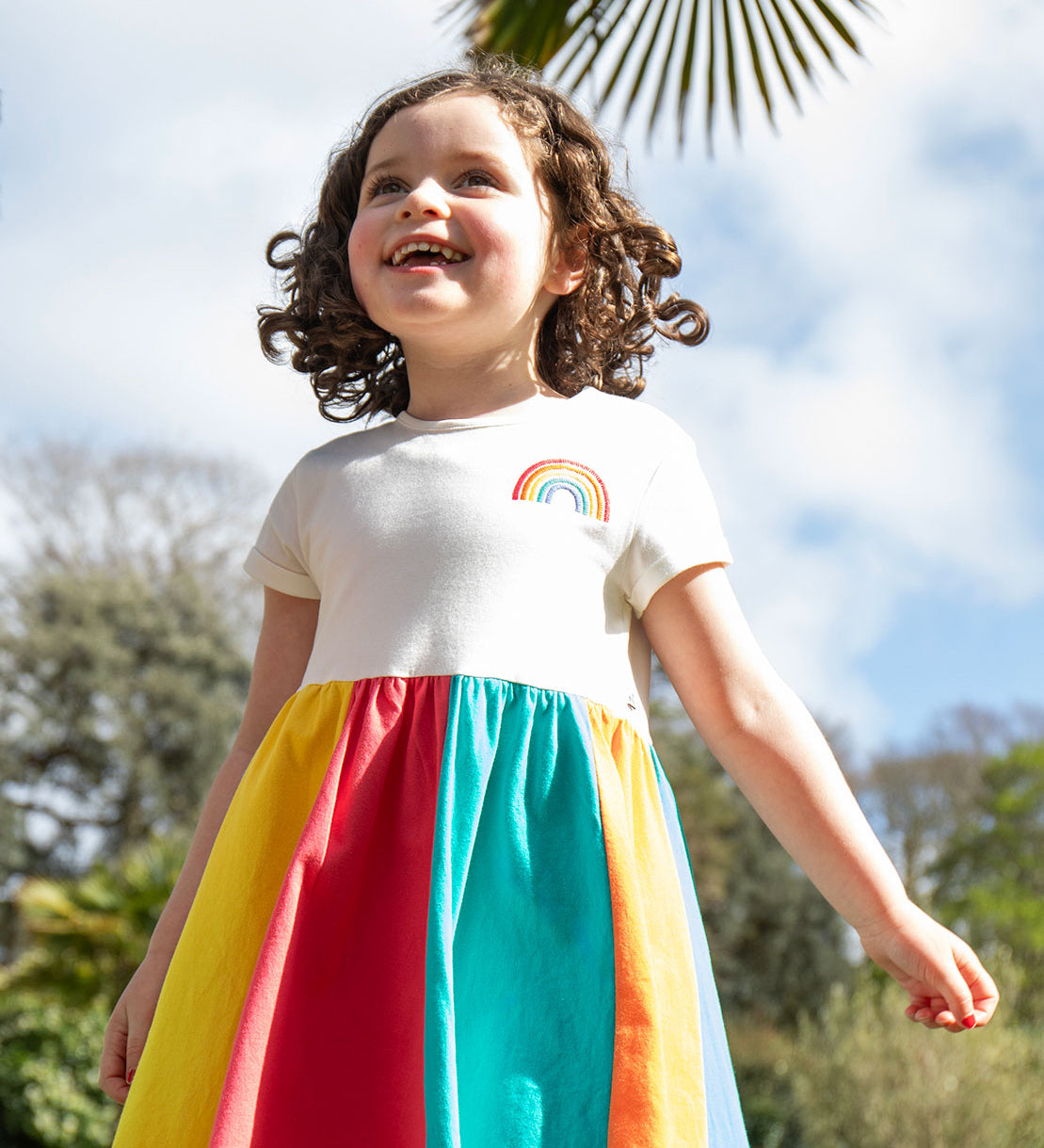 A child wearing the Frugi Rainbow Jersey Dress.