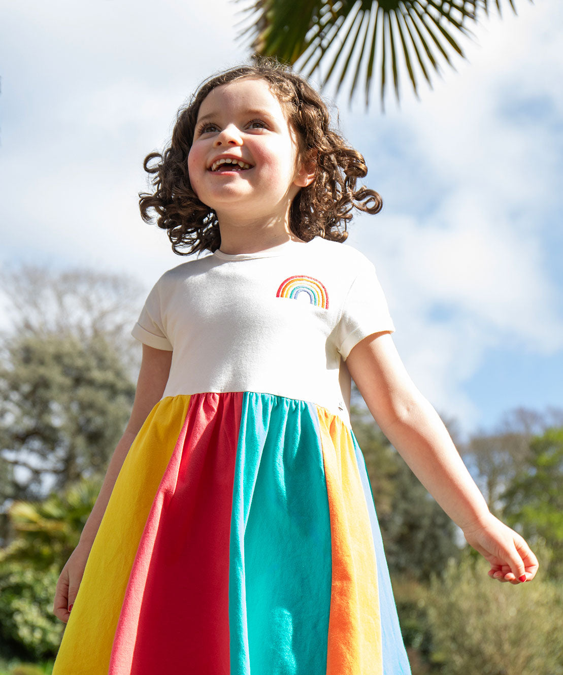 A child wearing the Frugi Rainbow Jersey Dress.