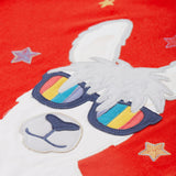 Close up of the Frugi kids red llama character t-shirt showing the white and grey llama appliqué wearing rainbow sunglasses and surrounded by different coloured embroidered stars on red organic cotton fabric