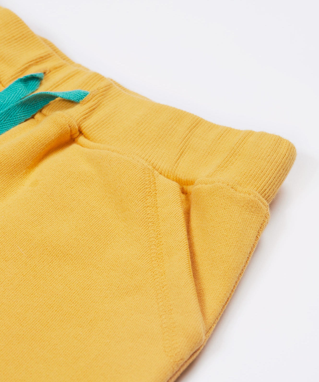 Close up of the Frugi kids bumblebee Samson shorts showing the turquoise waist drawstring and front pocket detail on yellow organic cotton fabric