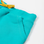 Close up of the Frugi kids sea moss Samson shorts showing the yellow waist drawstring and front pocket detail on turquoise organic cotton fabric