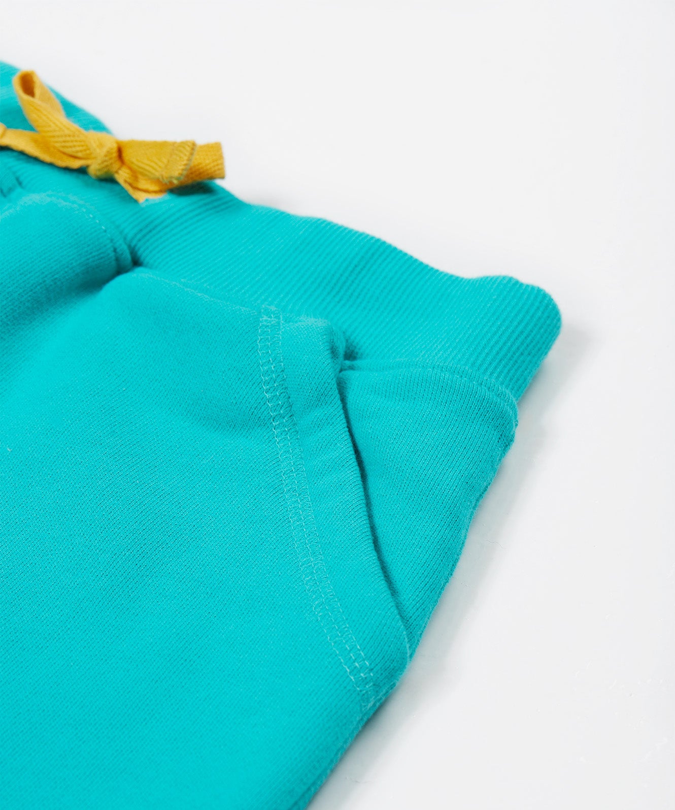 Close up of the Frugi kids sea moss Samson shorts showing the yellow waist drawstring and front pocket detail on turquoise organic cotton fabric