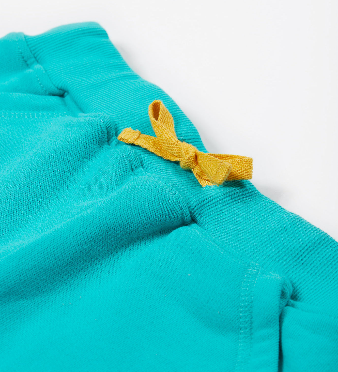 Close up of the Frugi kids sea moss Samson shorts showing the yellow waist drawstring on turquoise organic cotton fabric