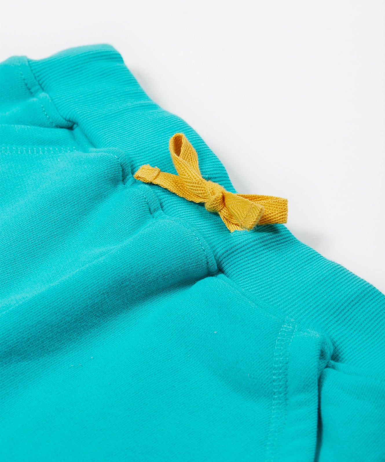 Close up of the Frugi kids sea moss Samson shorts showing the yellow waist drawstring on turquoise organic cotton fabric