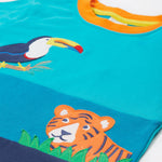 A close up of the Frugi sea, land, canopy short sleeve -shirt. Showing the orange neck trim and the toucan and  tiger appliqué stitched on a blue organic cotton fabric