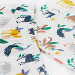 A close up of the Frugi kids snooze wildlife pyjama set showing the prints of different wild animals and the elastic waist band on the shorts on white organic cotton fabric