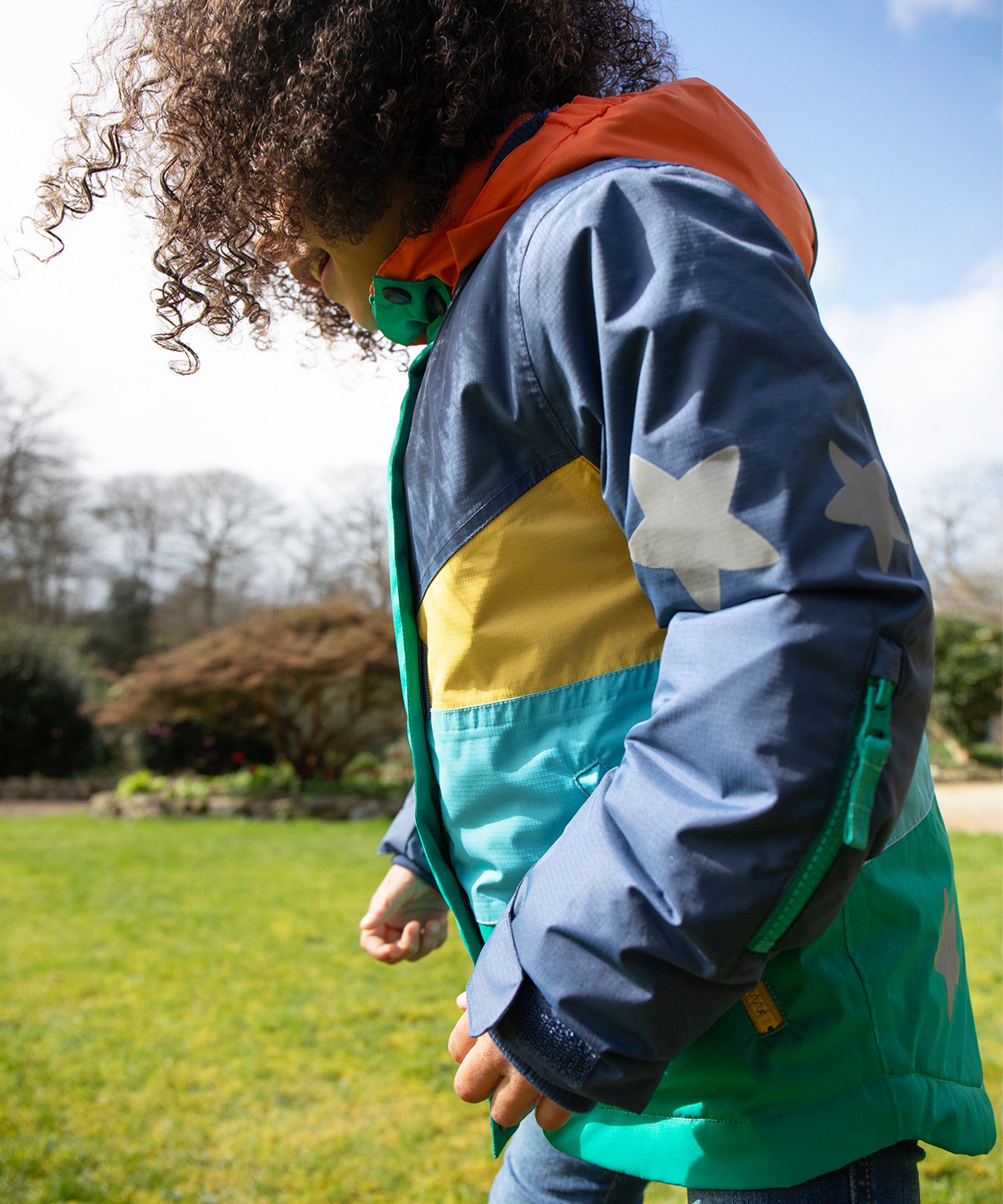 A child smiling and wearing the Frugi Snow & Ski Coat - Iguana Colourblock