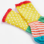 A close up of the Frugi kids Freya sock. Showing the yellow spotted sock with a striped design and light pink frill on organic cotton fabric