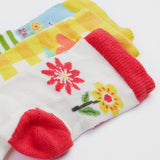 A close up of the Frugi kids spring 3 pack socks - GOTS organic kids socks which features a white sock with a pink trim and flowers design. A yellow gingham sock with a flower design and a green striped sock with a rabbit design.