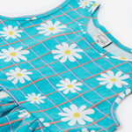 Close up of the Frugi kids summer holiday dress. Showing the sleeveless and neck trim detail with the daisy pattern on a blue check organic cotton fabric.