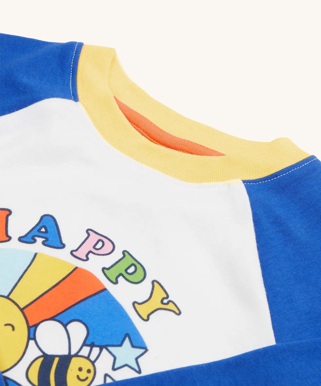 A close up of the collar on the A close up of the graphic design on the Frugi Tamar Raglan Top - White with Be Happy. 