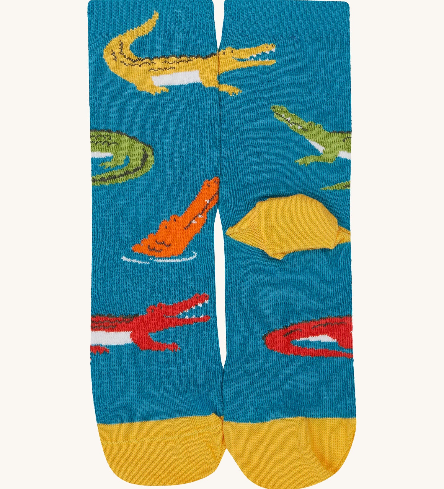 A close up of the Frugi teal multicoloured crocodile sock a soft GOTS cotton sock features a yellow sole and toes panel