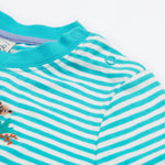 A close up of the Frugi kids moss stripe wildlife t-shirt. Showing the shoulder popper fasteners for easy fitting with a light blue neck trim on a blue and white stripe organic cotton fabric