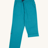 Frugi kids trousers in green, blue, turquoise colour on a cream background.