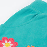 A close up of the shorts from the Frugi kids bee stripe outfit. Showing the pocket detail and flowers applique on a light blue organic cotton fabric