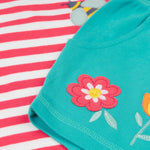 A close up of Frugi kids bee watermelon stripe outfit showing the bee and  flowers applique on a light blue, pink and white organic cotton fabric