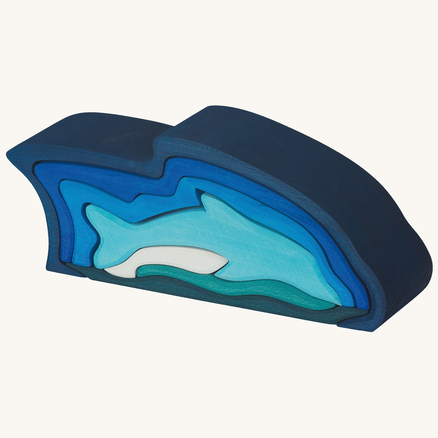 Wooden dolphin puzzle set in various shades of blue. The set includes a mixture of outlines and full-body shapes. A combination of pieces are stacked together forming a dolphin diving scene.