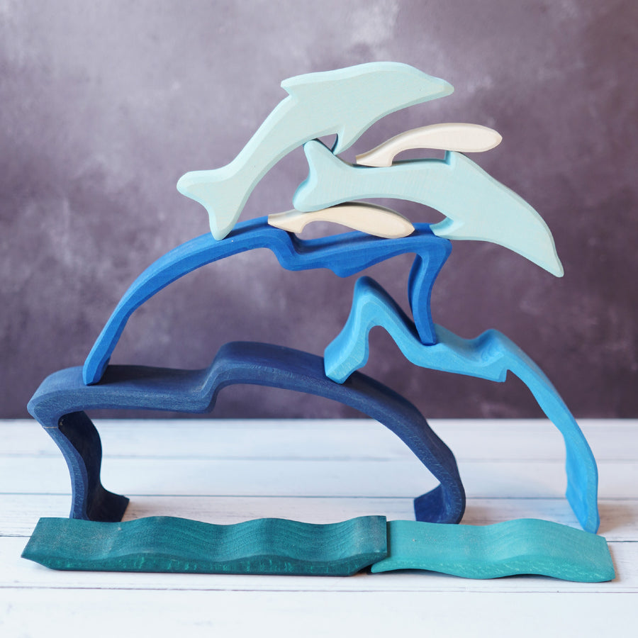 Wooden dolphin puzzle set in various shades of blue. The set includes a mixture of outlines and full-body shapes.