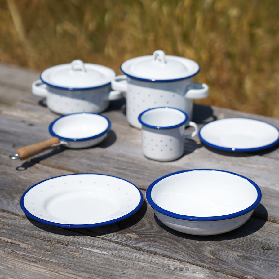 A Glückskäfer Enamel Plate pictured next to a bowl on a wooden surface outdoors