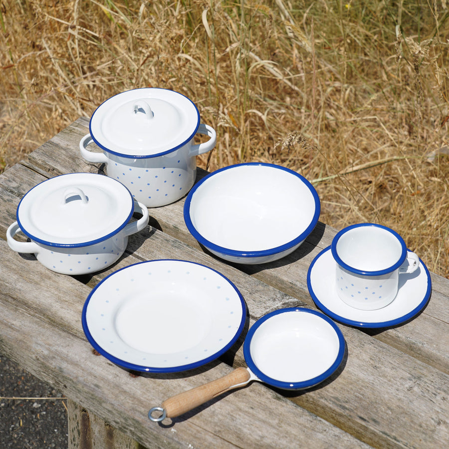 A collection of Glückskäfer Enamel kitchen toys pictured on a wooden surface outdoors