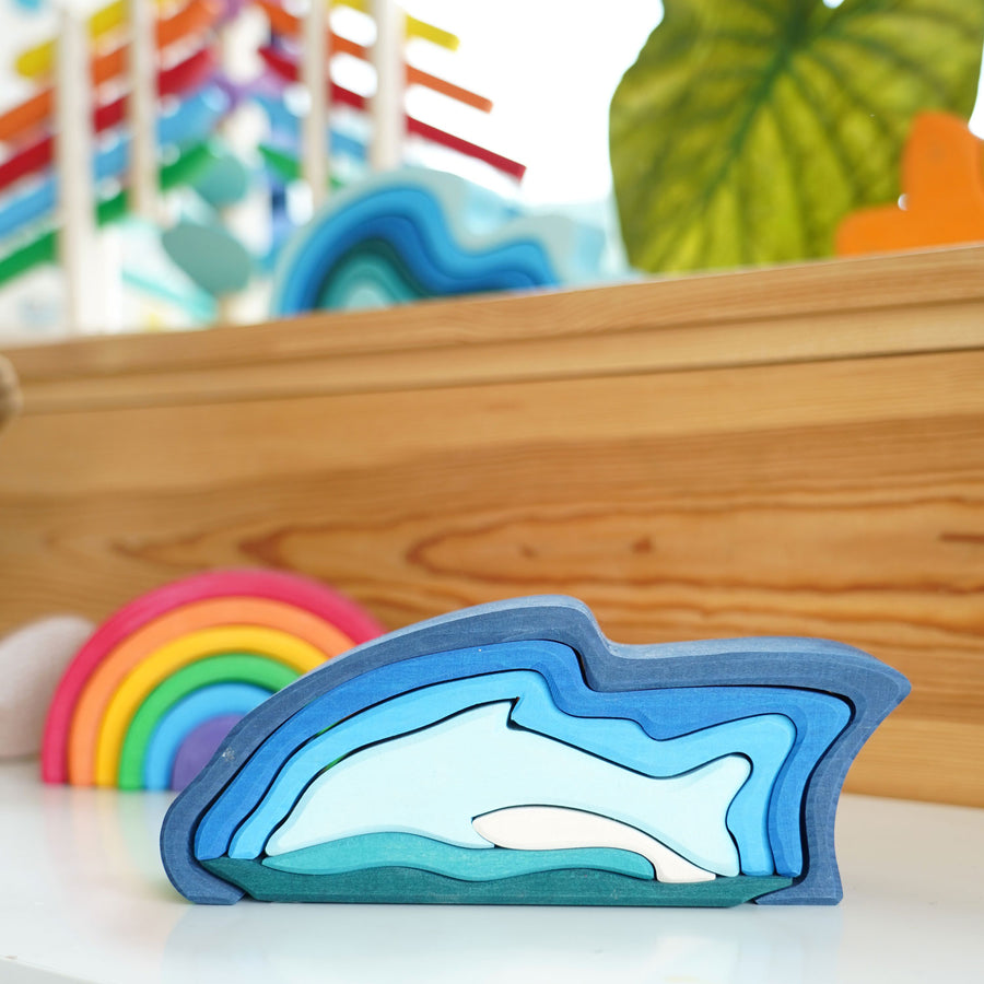 Wooden dolphin puzzle set in various shades of blue. The set includes a mixture of outlines and full-body shapes.