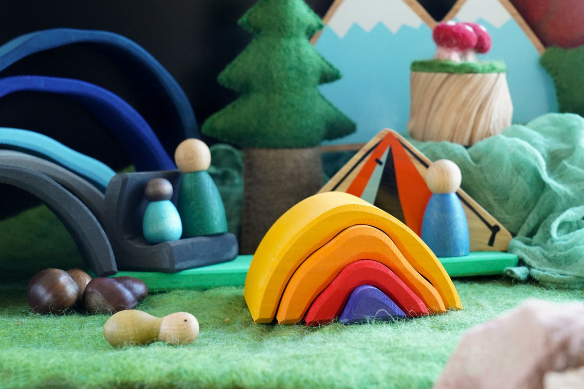 Close up of the Gluckskafer wooden bonfire on a green felt base surrounded by Grapat nins and lanka kade dan y ser toys in a campfire scene