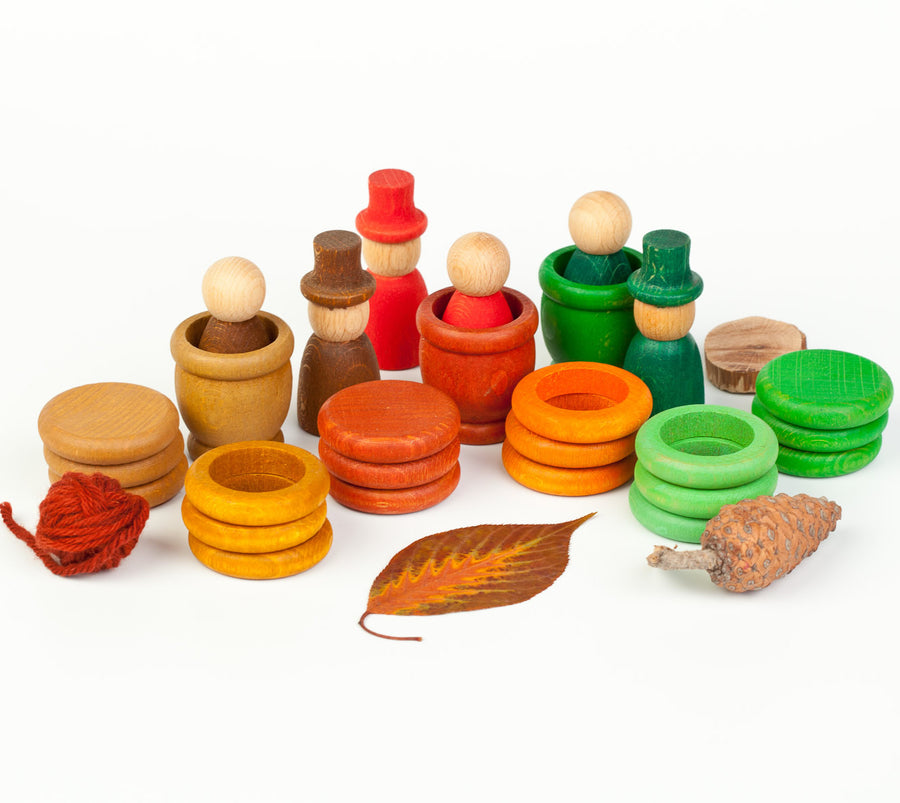 a peg people play set in the colours of autumn. Wooden tray background.