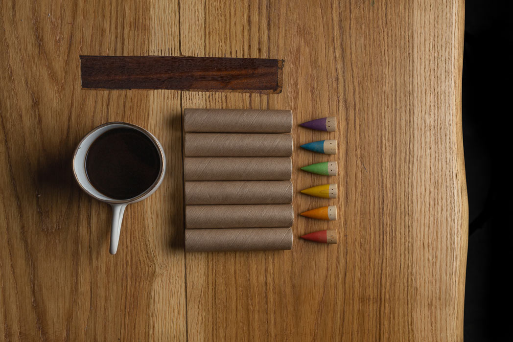 Birds eye view of 6 Grapat Baby Sticks lined up on a wooden coffee table next to a white mug of coffee.