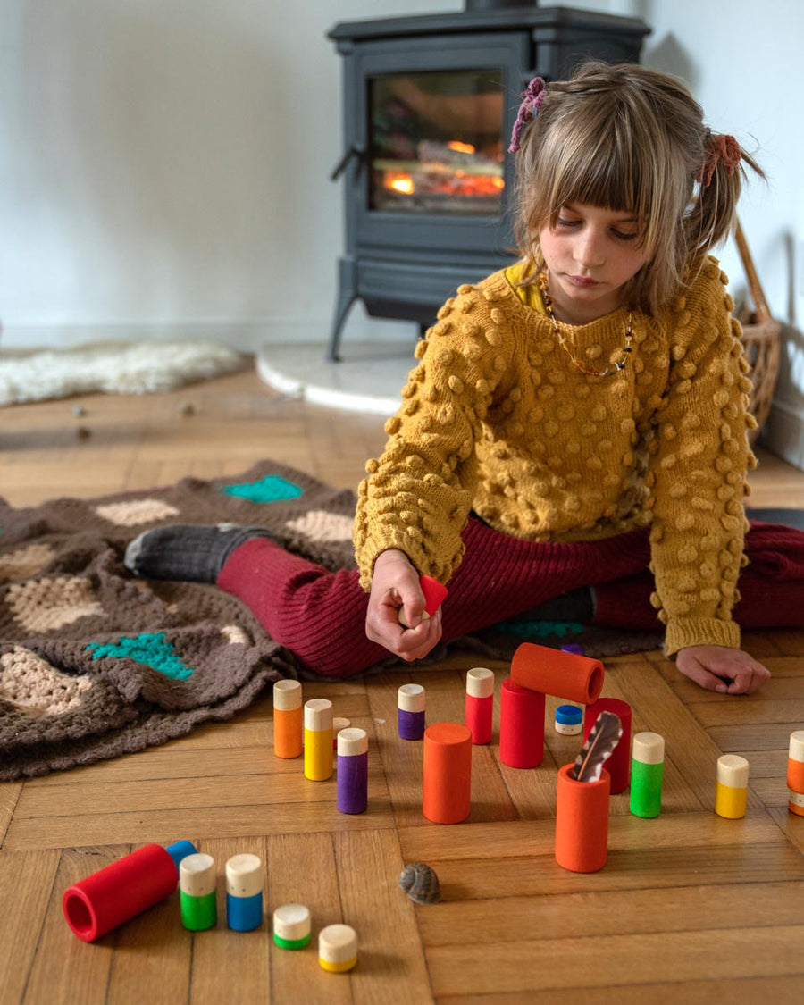 Child sat on the floor playing with the Grapat rainbow Lo stacking tubes