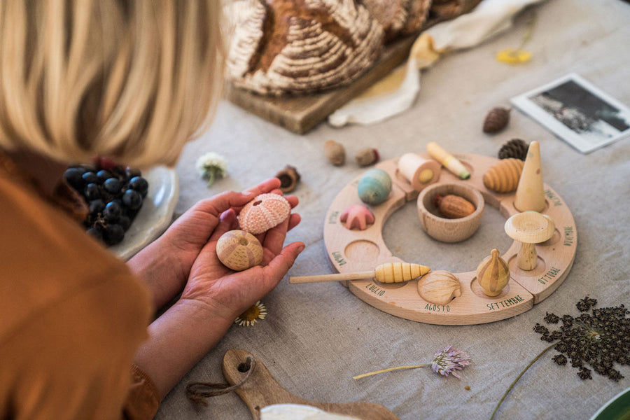 Close up of a child holding pieces of the Grapat Wonders toy set next to a perpetual ring calendar on a grey table cloth