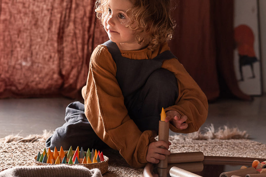 Young girl placing Grapat Baby Stick into a cardboard tube on the floor.