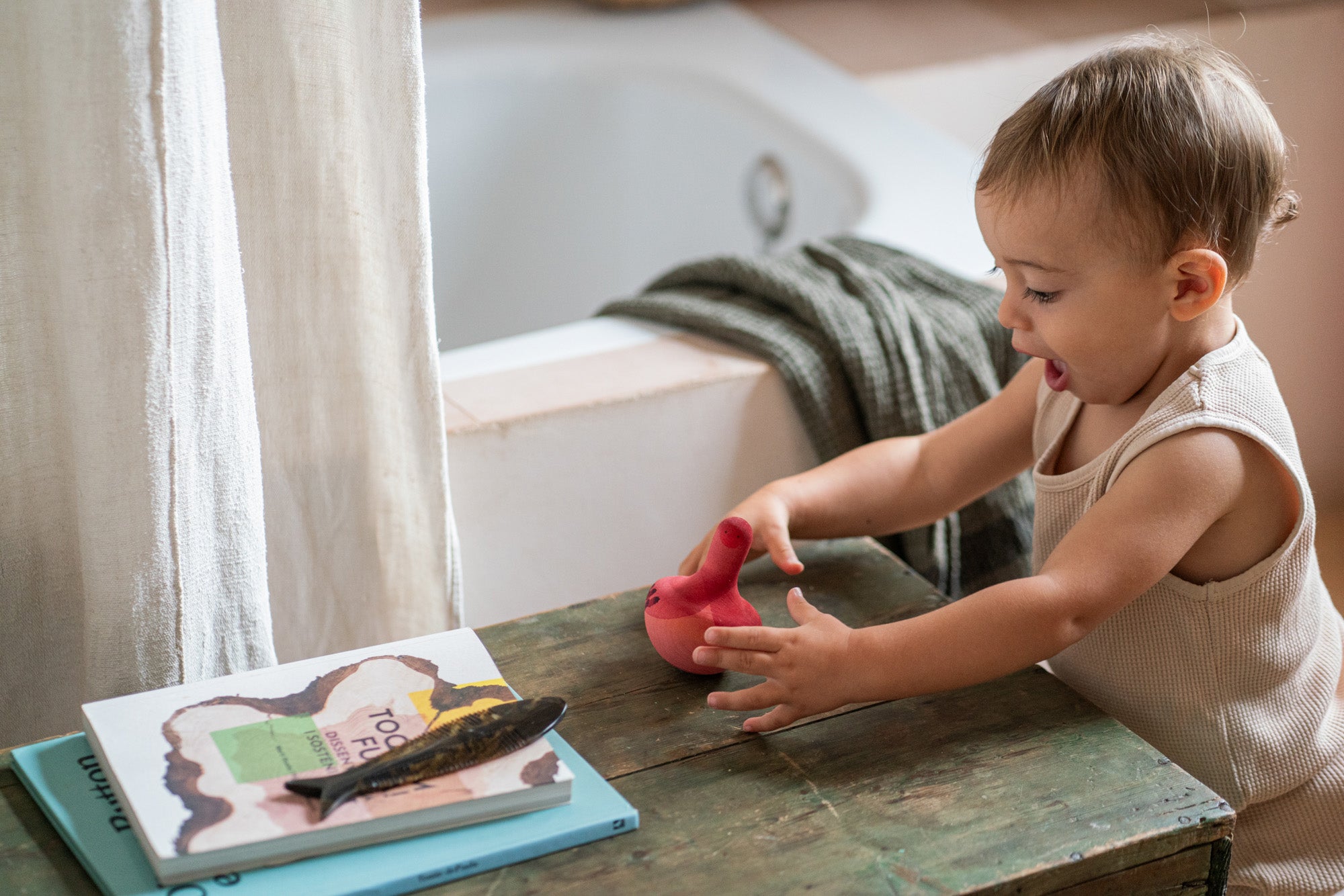 A child playing with the Grapat wooden pink chill bird on a table