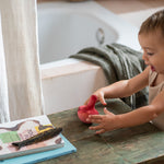 A child playing with the Grapat wooden pink chill bird on a table