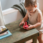 A child playing with the Grapat wooden pink chill bird next to a wooden table 