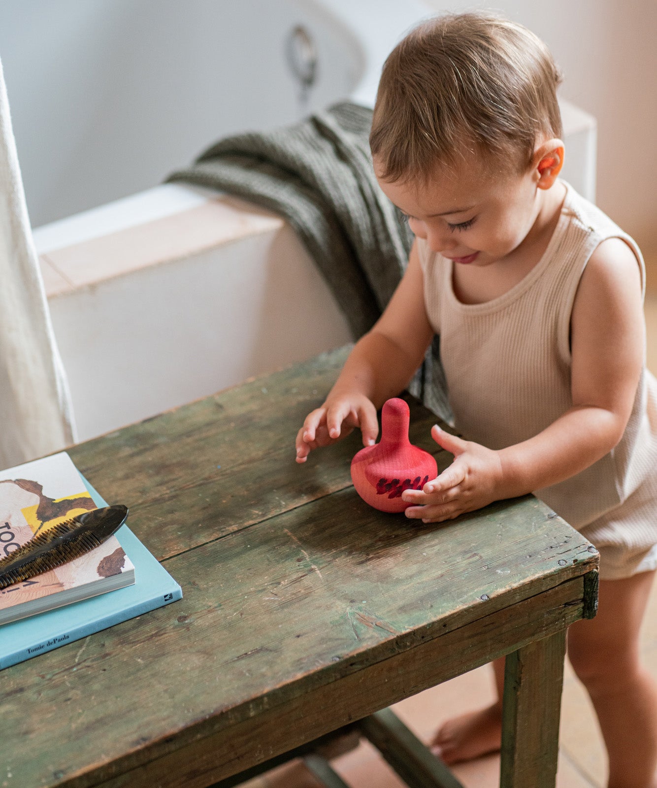 A child playing with the Grapat wooden pink chill bird next to a wooden table 