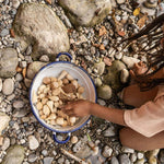 Close up of a child playing with the Grapat plastic-free wooden mandala pieces in a white bowl on some small rocks