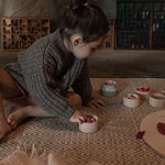 Girl playing on the floor with 6 small grey pots