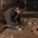 Girl playing on the floor with 6 small grey pots